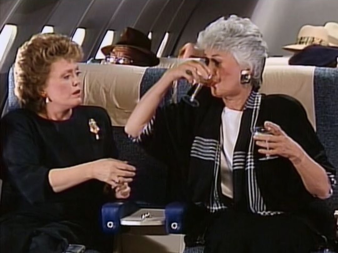 Dorothy drinking Blanche's champagne on a plane